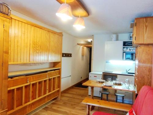 une cuisine avec des placards en bois et une table avec des tabourets dans l'établissement Studio au pied des pistes, idéal pour 4, bien équipé, balcon - FR-1-771-81, à Les Adrets