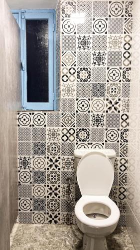 a bathroom with a toilet and a black and white tiled wall at Ithaka Raml Hostel in Alexandria