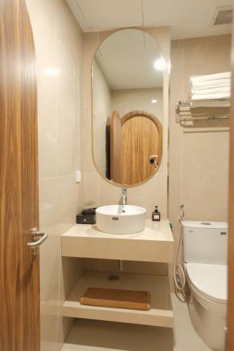 a bathroom with a sink and a mirror and a toilet at Mê Stay Cát Bà in Cat Ba