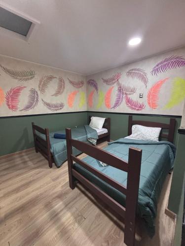 a room with two beds and a wall with feathers at Hotel Minga in Copiapó