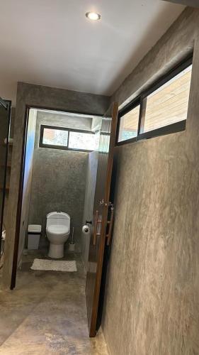 a bathroom with a toilet and some windows at Cabina Tropically in Santa Cruz