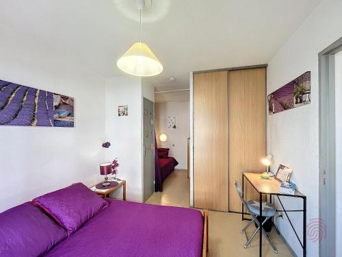 - une chambre avec un lit violet et un bureau dans l'établissement Joli F2 avec balcon, animaux acceptés - FR-1-451-216, à Lamalou-les-Bains