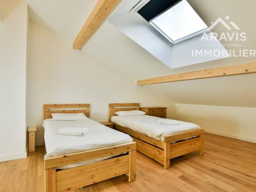 - 2 lits dans une chambre avec une lucarne dans l'établissement Appartement spacieux à Samoëns, proche centre - FR-1-391-200, à Samoëns