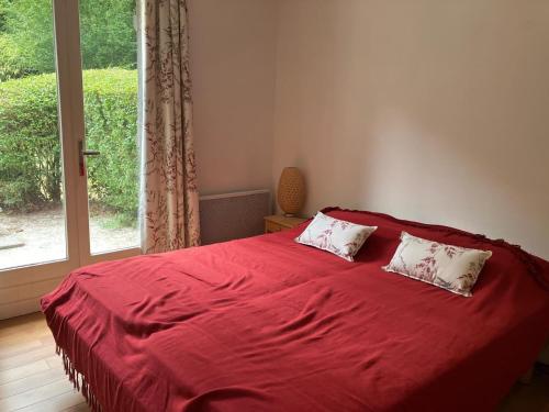 un lit rouge avec deux oreillers dans une chambre avec une fenêtre dans l'établissement Charmante maison avec cheminée et grande terrasse - FR-1-712-91, à Villers-sur-Mer