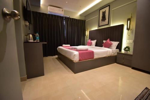 a bedroom with a large bed with pink pillows at Dhanvantari Luxury Hotel Near Kokilaben Dhirubhai Ambani Hospital Mumbai in Mumbai