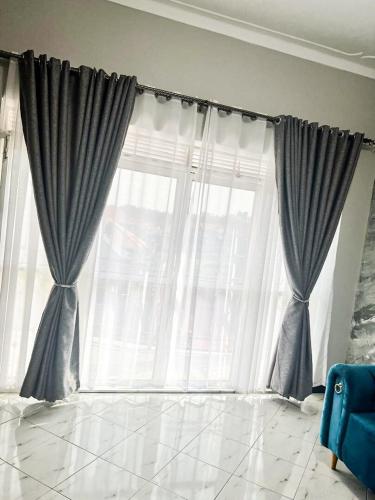 a living room with a large window with curtains at Relax, Unwind, 2 Bed Haven near Kavumba Rec Center in Wakiso