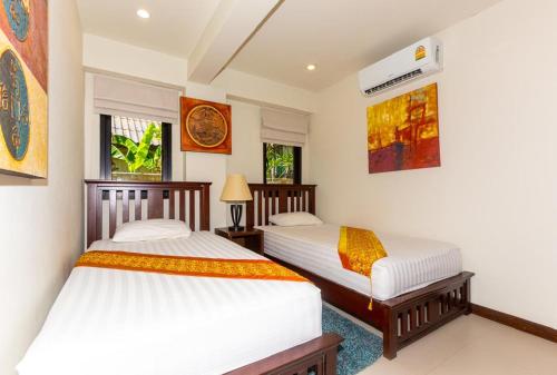 Dos camas individuales en una habitación con dos ventanas. en Naiharn beach sands Apartment, en Nai Harn Beach