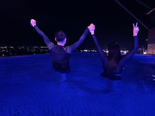 a man and a woman sitting in the water at night at 1106 LaGrande2 11floor rooftop swiming angeles Walking street in Angeles
