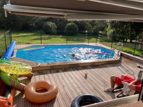 - une piscine sur une terrasse en bois avec des personnes dans l'établissement Maison de campagne de plein pied., à Plougonven