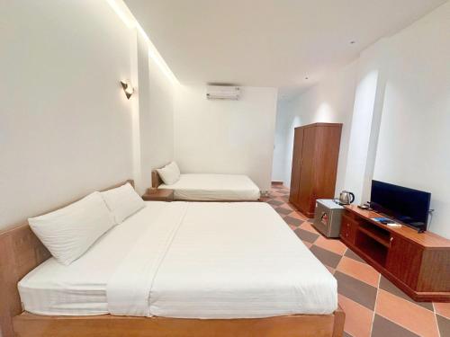a bedroom with two beds and a television in it at Le Huynh Mui Ne Hotel in Mui Ne