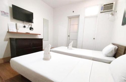 two beds in a white room with a tv at Sulit Budget Hotel VMapa in Manila