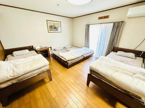 a room with three beds and a window at Nono teru Narita in Narita