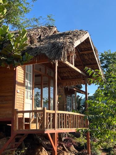 a wooden house with a thatched roof at MAMA's House Mộc Châu in Mộc Châu