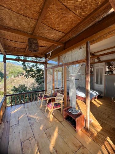 a large wooden deck with a bed and a table at MAMA's House Mộc Châu in Mộc Châu