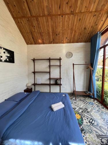 a bedroom with a blue bed and a wooden ceiling at MAMA's House Mộc Châu in Mộc Châu