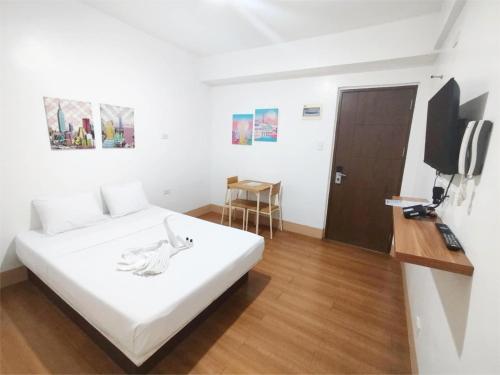 a bedroom with a white bed and a television at Sulit Budget Hotel VMapa in Manila