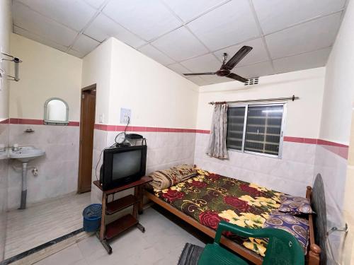 a bedroom with a bed and a tv and a sink at Lodge Bikash in Siliguri