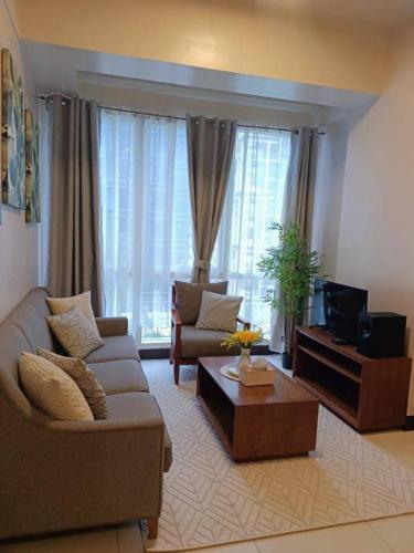 a living room with a couch and a tv at Mactan Newtown in Lapu Lapu City