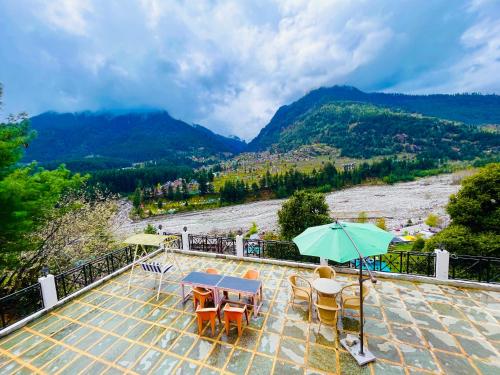a patio with a table and chairs and an umbrella at Hotel Hollywood Vibes #riverview #premium rooms #prime location #most awarded #parking #top rated #open terrace #lawn #best selling hotel in manali in Manāli