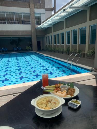 a tray of food on a table next to a swimming pool at Grand Zuri Pematangsiantar in Pematangsiantar