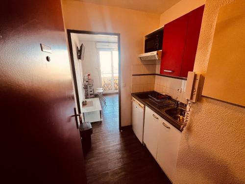 une cuisine avec des placards blancs et une porte rouge dans l'établissement Terrasse du soleil, Studio proche Gare Montpellier, à Montpellier