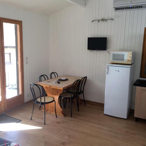 a kitchen with a table with chairs and a microwave at Manoir de Champvert in Les Vans