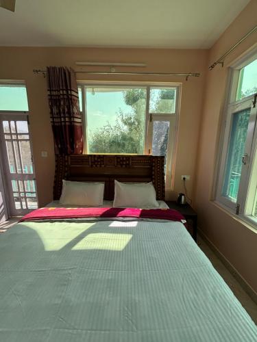 a bedroom with a large bed with two windows at Green Valley View Homestay in Shimla