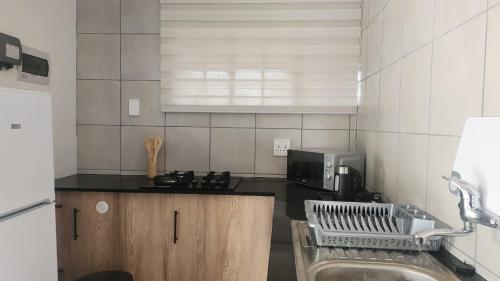 a kitchen with a sink and a counter top at Foundation Stones Lodge Summerstrand in Gqeberha