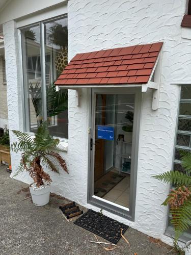 a door with a red roof on a house at Waiake Beach Apartments in Auckland