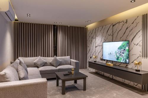a living room with a couch and a flat screen tv at Medad Apartments Al Hamra in Al Khobar