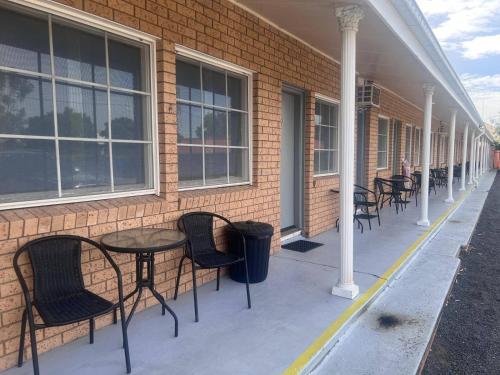 a row of tables and chairs next to a brick building at Coonamble Motel in Coonamble