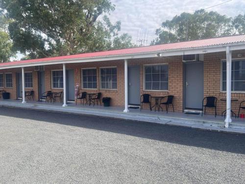 a brick building with chairs and tables on the porch at Coonamble Motel in Coonamble
