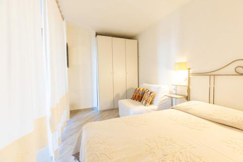 a white bedroom with two beds and a chair at Lulamax Sardegna in Budoni