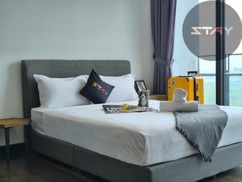 a bedroom with a bed with white sheets and a yellow suitcase at Almas Warm N Comfy 2Pax Puteri Harbour BySTAY in Nusajaya