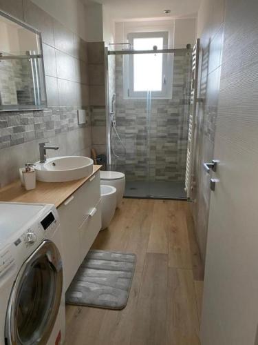 a bathroom with a sink and a washing machine at HOME LEOPARDI humanitas,forum,ieo INTERO APPARTAMENTO in Rozzano