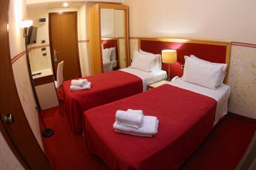a hotel room with two beds with red sheets at Hotel Palace Masoanri's in Reggio Calabria