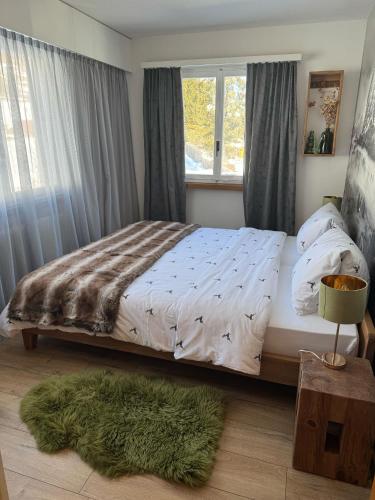a bedroom with a bed and a window and a green rug at Berg-Bijou Scuol in Scuol
