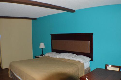 a bedroom with a bed and a blue wall at Sun Down Lodge in Locust Grove