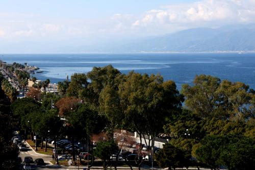 a view of the ocean from a city with trees at Hotel Palace Masoanri's in Reggio Calabria