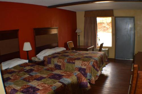a hotel room with a bed and a desk and a window at Sun Down Lodge in Locust Grove