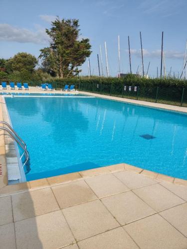 une grande piscine bleue avec des chaises bleues. dans l'établissement Appartement 4 personnes Arzon, entre plage et Port Crouesty, à Arzon
