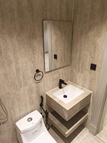 a bathroom with a sink and a toilet and a mirror at Medad Apartments Al Hamra in Al Khobar