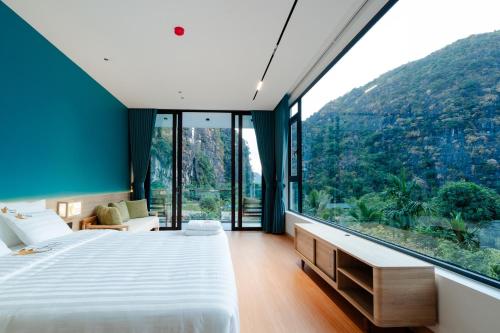 a bedroom with a large window with a mountain view at Tam Coc Wonderland Lodge in Ninh Binh