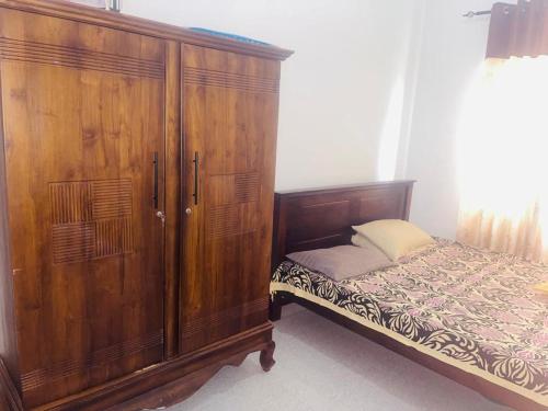 1 dormitorio con armario de madera y cama en kurunegala deco apartement, en Kurunegala