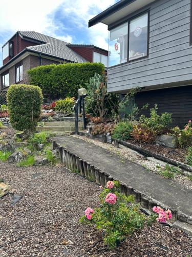 a house with a garden with flowers in front of it at A Home Away from Home - Bucklands Beach Luxury 3-Bedroom Garden Villa in Auckland