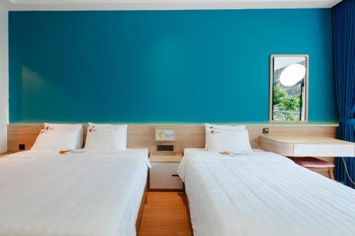 two beds in a room with a blue wall at Tam Coc Wonderland Lodge in Ninh Binh