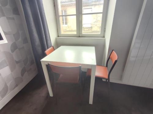 une table blanche et des chaises dans une pièce avec une fenêtre dans l'établissement Appartement 3 personnes quartier Chartrons avec climatisation, à Bordeaux