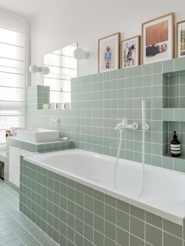 une salle de bains en carrelage vert avec une baignoire et un lavabo. dans l'établissement Appartement familial conçu par un architecte, à Levallois-Perret