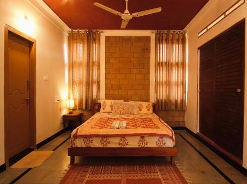 a bedroom with a bed and a ceiling fan at EcoMinimalist Home by the River in Seringapatam