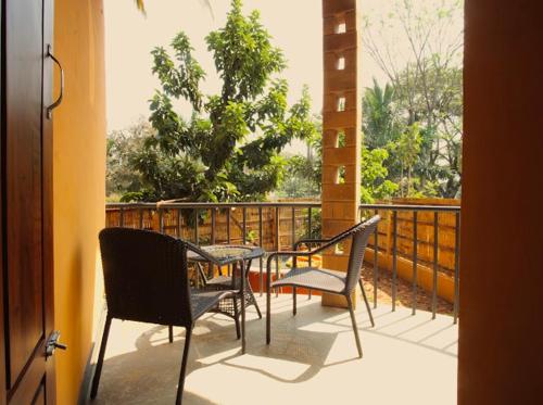a patio with a table and chairs on a balcony at EcoMinimalist Home by the River in Seringapatam